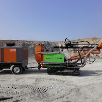 Track-mounted drill towing portable compressor.